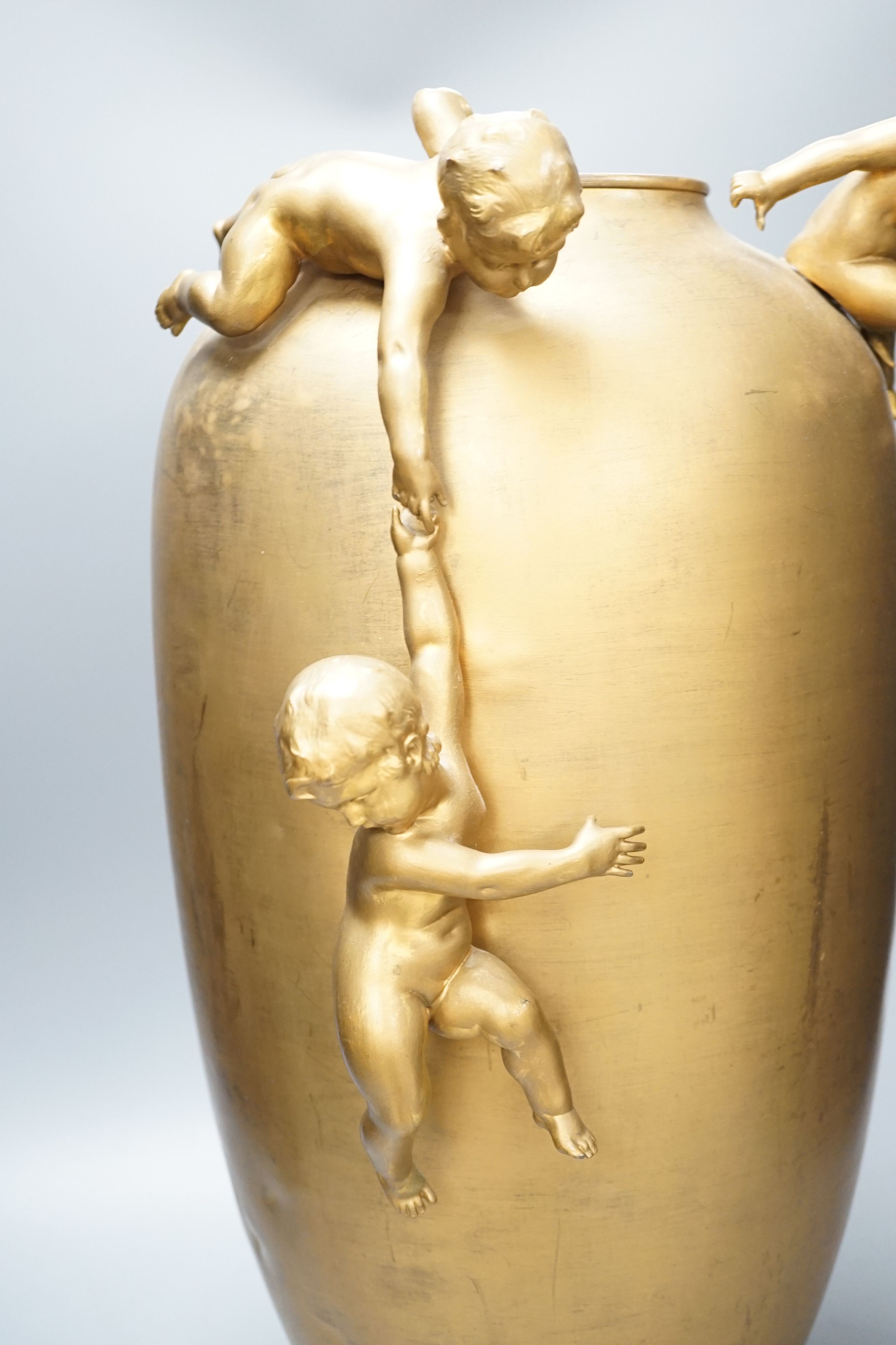 A large Kayser gilt metal ovoid jar, with playful cherubs, 55cm.
